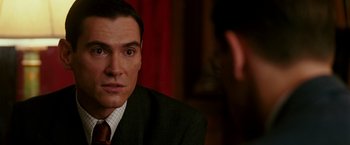 Movie still from “The Good Shepherd” (2006), directed by Robert De Niro – A person wearing a suit and tie; Close Up shot, Over the shoulder angle