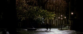 Movie still from “The Good Shepherd” (2006), directed by Robert De Niro – Two people are walking in the rain in front of a building; Extreme Wide shot, High angle