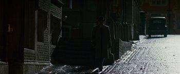 Movie still from “The Good Shepherd” (2006), directed by Robert De Niro – A man wearing a hat and a coat walking down a street; Wide shot, Over the shoulder angle