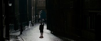Movie still from “The Good Shepherd” (2006), directed by Robert De Niro – A person walking down a street at night; Wide shot, High angle