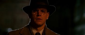 Movie still from “The Good Shepherd” (2006), directed by Robert De Niro – A man in a hat and glasses wearing a suit and tie; Close Up shot, Low angle