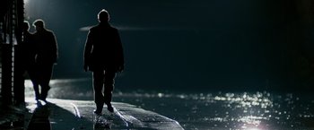 Movie still from “The Good Shepherd” (2006), directed by Robert De Niro – A man standing on a surfboard in the dark; Wide shot, Low angle