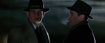 Movie still from “The Good Shepherd” (2006), directed by Robert De Niro – A man in a hat and a man smoking a cigarette; Close Up shot, Over the shoulder angle