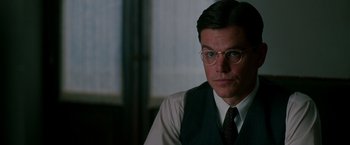 Movie still from “The Good Shepherd” (2006), directed by Robert De Niro – A person wearing glasses and a tie; Close Up shot, Over the shoulder angle