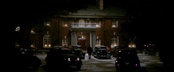 Movie still from “The Good Shepherd” (2006), directed by Robert De Niro – A person standing in front of a building with cars parked in front of it; Extreme Wide shot, Low angle