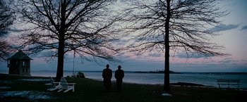 Movie still from “The Good Shepherd” (2006), directed by Robert De Niro – Two men standing next to each other near a body of water; Extreme Wide shot, Over the shoulder angle