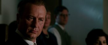 Movie still from “The Good Shepherd” (2006), directed by Robert De Niro – A man in a suit and tie standing next to another man in a suit; Close Up shot, Over the shoulder angle