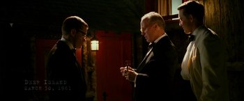 Movie still from “The Good Shepherd” (2006), directed by Robert De Niro – A man in a suit and tie standing next to another man; Medium shot, Over the shoulder angle
