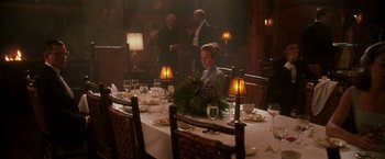 Movie still from “The Good Shepherd” (2006), directed by Robert De Niro – A woman sitting at a dinner table in front of a candle lit table; Wide shot, Over the shoulder angle