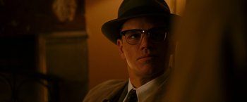 Movie still from “The Good Shepherd” (2006), directed by Robert De Niro – A man in a hat and glasses is sitting in a room; Close Up shot, Low angle