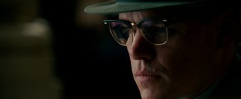 Movie still from “The Good Shepherd” (2006), directed by Robert De Niro – A person wearing glasses and a hat; Close Up shot, Low angle
