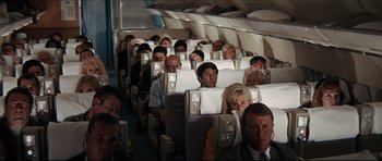 Movie still from “The Graduate” (1967), directed by Mike Nichols – A group of people sitting in a row of seats on an airplane; Wide shot, High angle
