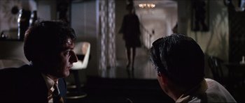 Movie still from “The Graduate” (1967), directed by Mike Nichols – Two people sitting in a room with a woman in the background; Medium shot, Over the shoulder angle