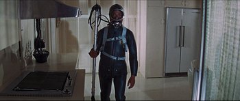 Movie still from “The Graduate” (1967), directed by Mike Nichols – A man in a full body suit holding a pole; Medium shot, Low angle