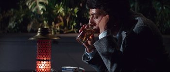 Movie still from “The Graduate” (1967), directed by Mike Nichols – A man in a suit and tie drinking from a glass; Medium shot, Over the shoulder angle