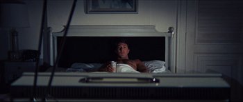 Movie still from “The Graduate” (1967), directed by Mike Nichols – A man laying in a bed with a drink in his hand; Medium shot, Low angle