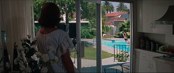 Movie still from “The Graduate” (1967), directed by Mike Nichols – A woman standing in front of an open sliding glass door looking out at a pool; Wide shot, Over the shoulder angle