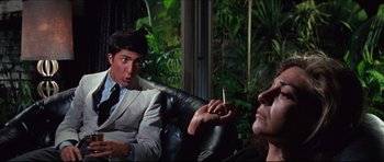 Movie still from “The Graduate” (1967), directed by Mike Nichols – A man sitting next to another man holding a cigarette; Medium shot, Over the shoulder angle
