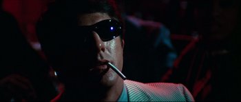 A man wearing sunglasses and holding a cigarette in his mouth