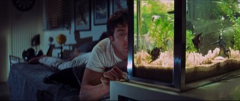 Movie still from “The Graduate” (1967), directed by Mike Nichols – A man looking into a fish tank with a fish in it; Medium shot, Low angle