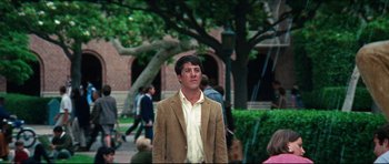 Movie still from “The Graduate” (1967), directed by Mike Nichols – A young man in a brown jacket is standing in the street; Wide shot, Over the shoulder angle