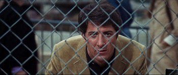 Movie still from “The Graduate” (1967), directed by Mike Nichols – A person behind a chain link fence; Close Up shot, Low angle