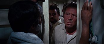 Movie still from “The Graduate” (1967), directed by Mike Nichols – A group of men standing next to each other in a room; Close Up shot, Over the shoulder angle