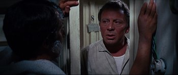 Movie still from “The Graduate” (1967), directed by Mike Nichols – A person standing next to a door; Close Up shot, Over the shoulder angle