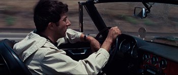 Movie still from “The Graduate” (1967), directed by Mike Nichols – A man driving a car on the street; Close Up shot, Over the shoulder angle