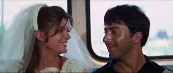 Movie still from “The Graduate” (1967), directed by Mike Nichols – A man and a woman smiling at each other on a bus; Close Up shot, Over the shoulder angle