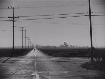Movie still from “The Grapes of Wrath” (1940), directed by John Ford – An empty road with power lines in the background; Extreme Wide shot, High angle