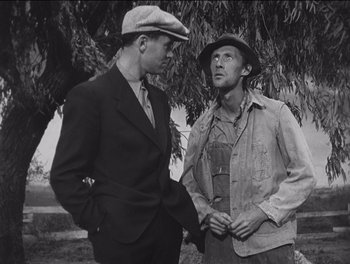 Movie still from “The Grapes of Wrath” (1940), directed by John Ford – Two men are standing in a field talking; Medium shot, Low angle