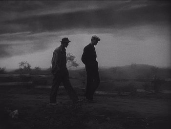Movie still from “The Grapes of Wrath” (1940), directed by John Ford – Two men are walking on a dirt road; Wide shot, Low angle