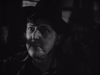 Movie still from “The Grapes of Wrath” (1940), directed by John Ford – An old man wearing a black hat and looking at the camera; Close Up shot, Over the shoulder angle