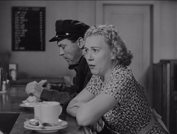 Movie still from “The Grapes of Wrath” (1940), directed by John Ford – An older man and woman sitting at a table with a cup of coffee; Medium shot, Low angle
