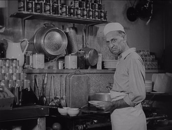 Movie still from “The Grapes of Wrath” (1940), directed by John Ford – An old photo of a man holding a pan in a restaurant kitchen; Medium shot, Low angle