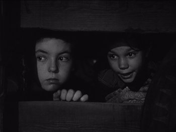 Movie still from “The Grapes of Wrath” (1940), directed by John Ford – Two young children peeking out of a wooden box; Close Up shot, High angle