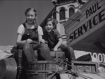 Movie still from “The Grapes of Wrath” (1940), directed by John Ford – Two young girls sitting on top of a wooden barrel; Wide shot, Low angle