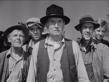 Movie still from “The Grapes of Wrath” (1940), directed by John Ford – A black and white photo of a group of men in hats; Medium shot, Low angle