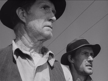 Movie still from “The Grapes of Wrath” (1940), directed by John Ford – A man in a hat and a man in a vest and a hat; Close Up shot, Low angle