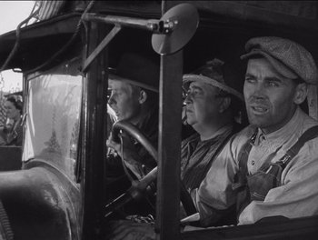 Movie still from “The Grapes of Wrath” (1940), directed by John Ford – A group of men sitting in the drivers seat of an antique car; Medium shot, Low angle