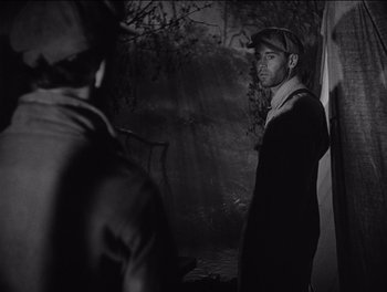 Movie still from “The Grapes of Wrath” (1940), directed by John Ford – A man standing in front of another man in a forest; Medium shot, Over the shoulder angle