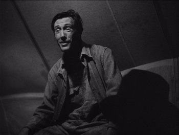 Movie still from “The Grapes of Wrath” (1940), directed by John Ford – Black and white photograph of a man sitting on a chair; Close Up shot, Low angle