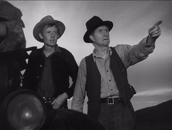 Movie still from “The Grapes of Wrath” (1940), directed by John Ford – Two men wearing hats and standing next to each other; Medium shot, Low angle