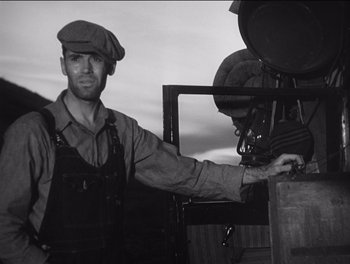 Movie still from “The Grapes of Wrath” (1940), directed by John Ford – A man wearing a hat and overalls standing in front of an oven; Medium shot, Low angle