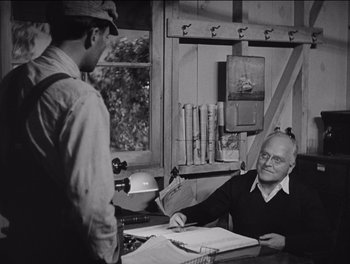 Movie still from “The Grapes of Wrath” (1940), directed by John Ford – An older man sitting at a table in front of another man; Medium shot, Over the shoulder angle
