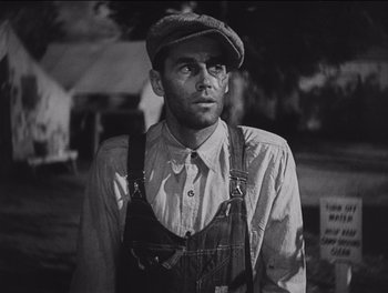 Movie still from “The Grapes of Wrath” (1940), directed by John Ford – A man in a hat and overalls standing in a field; Medium shot, Low angle