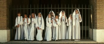 Movie still from “The Great Beauty” (2013), directed by Paolo Sorrentino – A group of children dressed as nuns standing in front of a fence; Wide shot, High angle