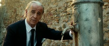 Movie still from “The Great Beauty” (2013), directed by Paolo Sorrentino – An older man in a suit and tie next to a water fountain; Close Up shot, Low angle