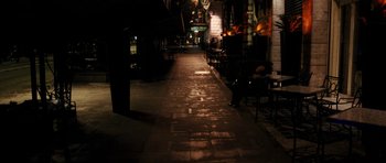 Movie still from “The Great Beauty” (2013), directed by Paolo Sorrentino – An empty sidewalk at night with tables and chairs; Wide shot, High angle
